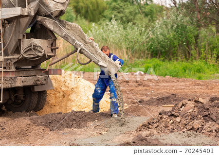 Construction worker laying cement or concrete into the foundation formwork 70245401