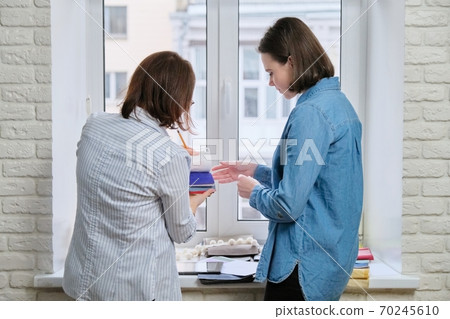 Women designers choosing fabrics and accessories for curtains 70245610