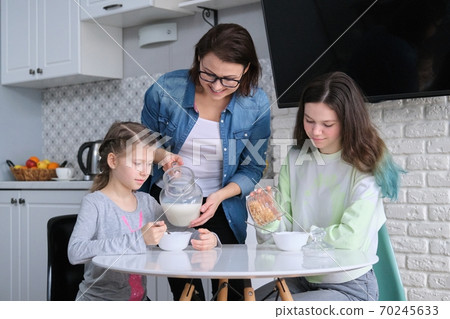 Children with mother eating at home in kitchen Children with mother eating at home in kitchen 70245633