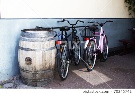 two bicycles near a barrel against the background of the coffee shop wall 70245741