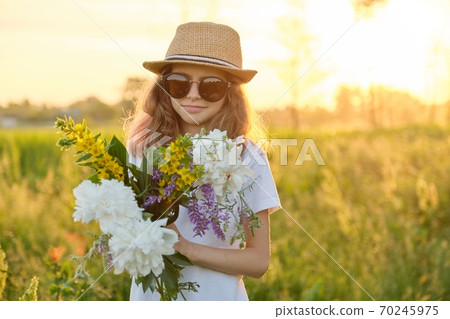 Portrait of child girl in hat sunglasses with bouquet of wildflowers Portrait of child girl in hat sunglasses with bouquet of wildflowers 70245975