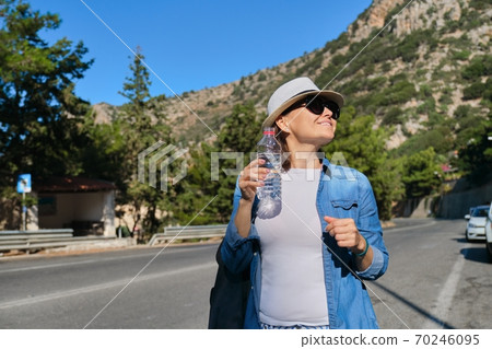 Adult female tourist removing thirst, drinking water from bottle Adult female tourist removing thirst, drinking water from bottle 70246095