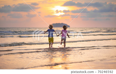 Child playing on ocean beach. Kid at sunset sea. Child playing on ocean beach. Kid at sunset sea. 70246592