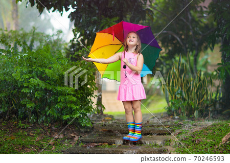 Kid with umbrella playing in summer rain. Kid with umbrella playing in summer rain. 70246593