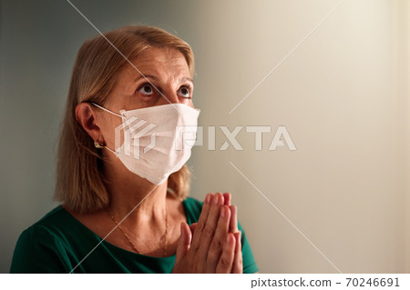 Woman in face mask praying for coronavirus victim Woman in face mask praying for coronavirus victim 70246691