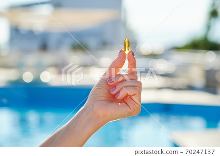 Sunny golden vitamin D oil capsule Omega-3 in woman hand Sunny golden vitamin D oil capsule Omega-3 in woman hand 70247137