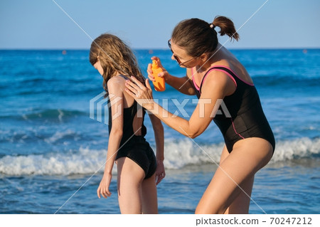 Mother applies sunscreen creams with spf to child 70247212