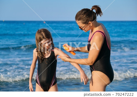 Mother applies sunscreen creams with spf to child 70247222