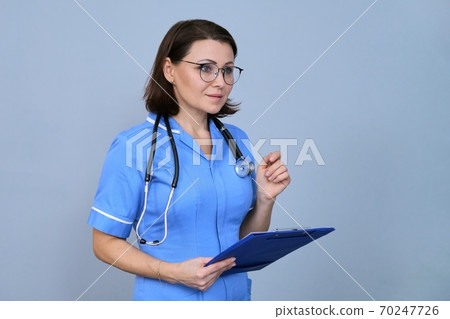 Portrait of mature nurse woman holding clipboard 70247726