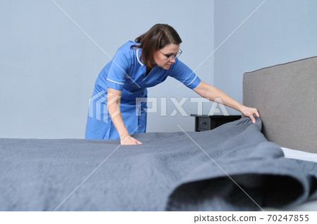 Cleaning service in hotel room, woman maid preparing guest room making bed Cleaning service in hotel room, woman maid preparing guest room making bed 70247855