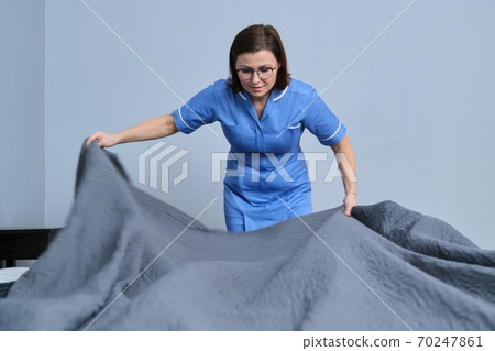Cleaning service in hotel room, woman maid preparing guest room making bed Cleaning service in hotel room, woman maid preparing guest room making bed 70247861