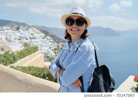 Happy mature woman tourist traveling on famous island Santorini Happy mature woman tourist traveling on famous island Santorini 70247865