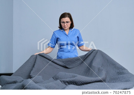 Chambermaid making guest bed in hotel bedroom Chambermaid making guest bed in hotel bedroom 70247875