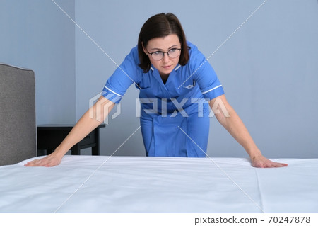 Cleaning service in hotel room, woman maid preparing guest room making bed Cleaning service in hotel room, woman maid preparing guest room making bed 70247878