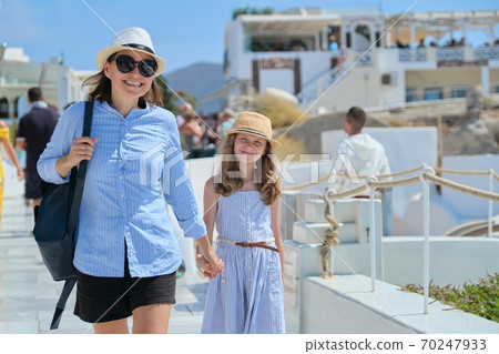 Mother walking with daughter child in famous tourist village Oia Santorini 70247933