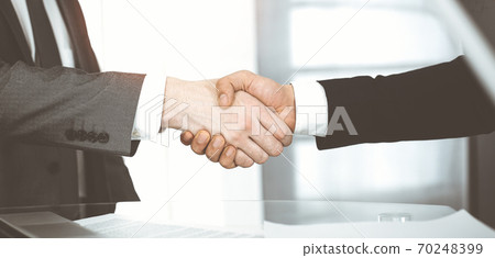 Unknown diverse business people are shaking hands finishing contract signing in sunny office, close-up. Business handshake concept Unknown diverse business people are shaking hands finishing contract signing in sunny office, close-up. Business handshake concept 70248399