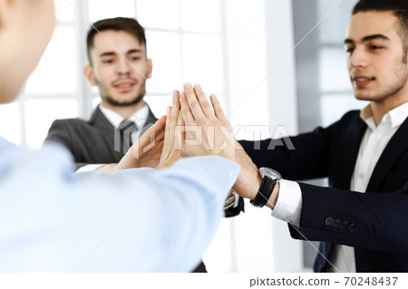 Business people group showing teamwork, joining hands and giving five to each other in modern office. Success concept 70248437