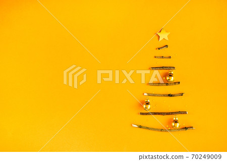 Creative Christmas tree made of wooden sticks. Minimal design on golden orange background. Creative Christmas tree made of wooden sticks. Minimal design on golden orange background. 70249009