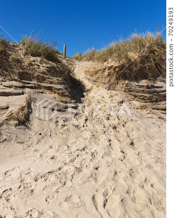 Looking up a sand dune at Montauk Beach with footprints from people leaving the beach Looking up a sand dune at Montauk Beach with footprints from people leaving the beach 70249193