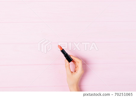 Minimal flat lay woman's hand holding open lipstick 70251065