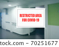 Sign on the door of a hospital corridor indicating an access area reserved for patients with covid-19 70251677