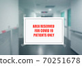 Sign on the door of a hospital corridor indicating an access area reserved for patients with covid-19 70251678