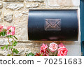 Vintage mailbox against a stone wall with roses around 70251683