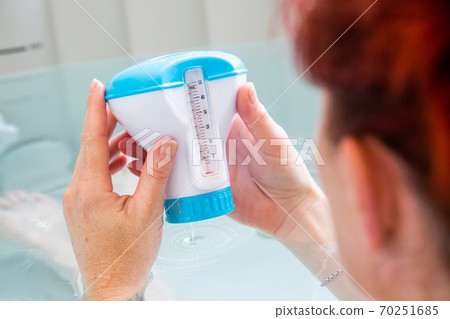 Woman in a hot tub bath controlling the water temperature 70251685