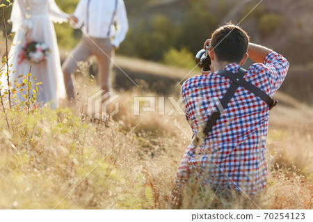 wedding photographer takes pictures of bride and groom wedding photographer takes pictures of bride and groom 70254123