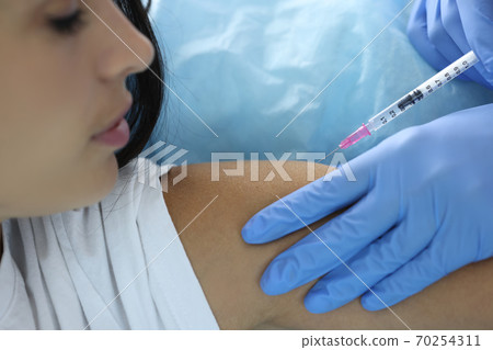 Doctor gives patient an injection in shoulder Doctor gives patient an injection in shoulder 70254311