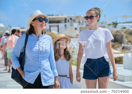Mother walking with two daughters in famous tourist village Oia Santorini Mother walking with two daughters in famous tourist village Oia Santorini 70254900