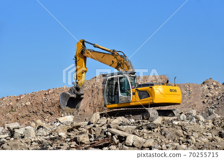 Yellow excavator at landfill for disposal of construction waste. Yellow excavator at landfill for disposal of construction waste. 70255715