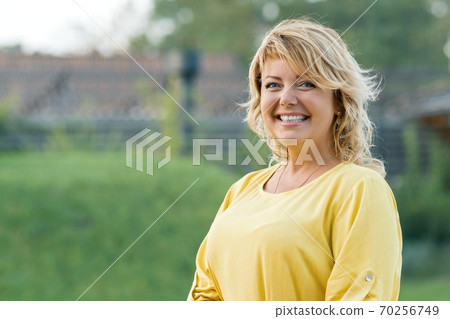 Outdoor portrait successful mature woman blonde in yellow dress Outdoor portrait successful mature woman blonde in yellow dress 70256749