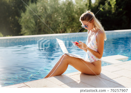 woman using laptop and work remotely near swimming pool woman using laptop and work remotely near swimming pool 70257907