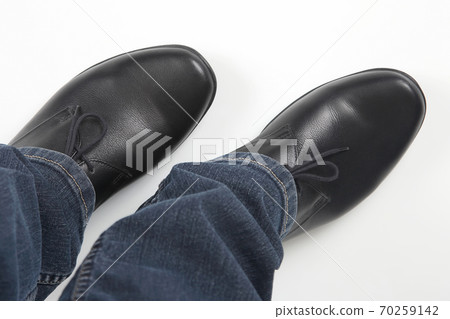 Men's legs in jeans and black classic shoes on white background Men's legs in jeans and black classic shoes on white background 70259142