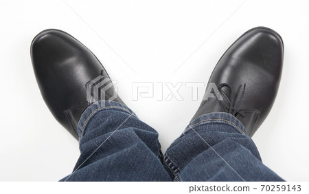 Men's legs in jeans and black classic shoes on white background 70259143