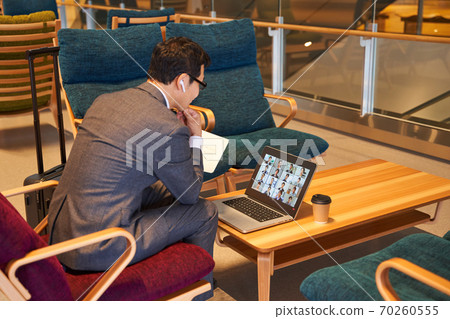 Middle businessman sitting on the sofa and having an online meeting Middle businessman sitting on the sofa and having an online meeting 70260555