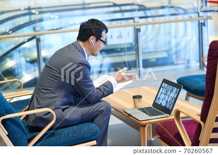 Middle businessman sitting on the sofa and having an online meeting 70260567