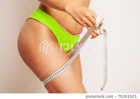 A slender woman measures the size of her leg A slender woman measures the size of her leg 70261925