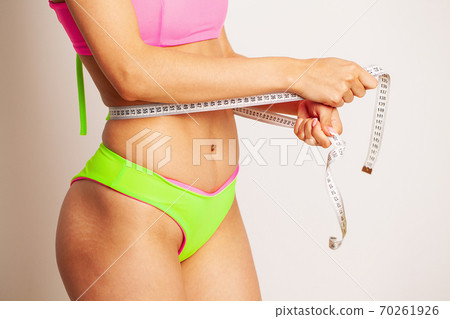 A slender woman measures the size of her waist A slender woman measures the size of her waist 70261926