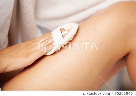 Woman arm holding dry brush to top of her leg, cellulite treatment and dry brushing. Woman arm holding dry brush to top of her leg, cellulite treatment and dry brushing. 70261946