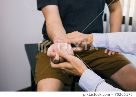 Physical therapist checks the patient wrist by pressing the wrist bone in clinic room. 70265175