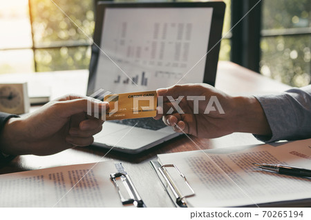 The bank clerk is talking to a customer who applied for a credit card service at the office. The bank clerk is talking to a customer who applied for a credit card service at the office. 70265194