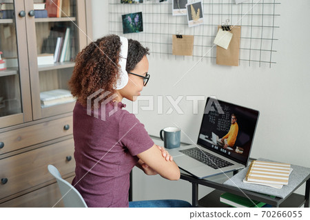 Young mixed-race diligent student having online lesson in home environment 70266055