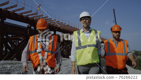 Professional engineers walking towards unfinished bridge 70266222