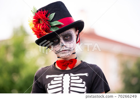 Spooky boy with painted face in halloween costume of skeleton with elegant hat Spooky boy with painted face in halloween costume of skeleton with elegant hat 70266249