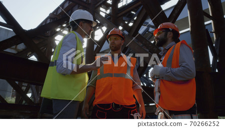 Inspector speaking with builders on construction site 70266252