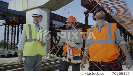 Male engineers discussing plan on construction site 70266335