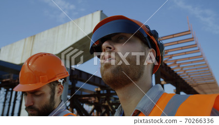 Builder in goggles speaking with colleague 70266336