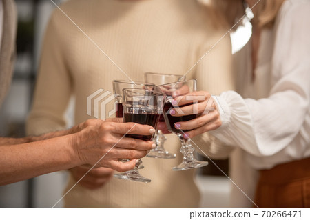 Hands of four family members in casualwear clinking with glasses of red wine 70266471